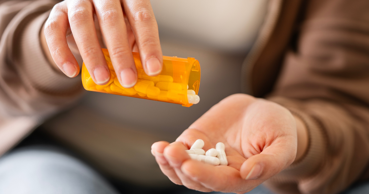 Person pouring white Nutritional Supplements capsules into their hand in Denver, CO